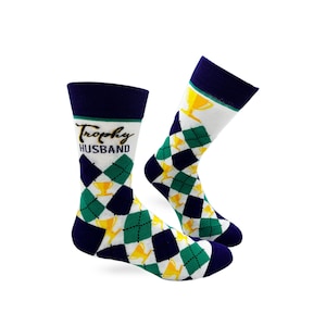 May include: A pair of white socks with a green and navy blue argyle pattern. The socks feature a gold trophy and the text "Trophy Husband".