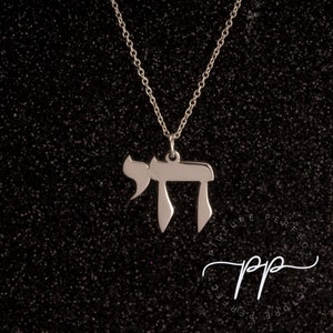 May include: A silver chain necklace with a pendant in the shape of the Hebrew letter Chai. The pendant is a simple, elegant design.