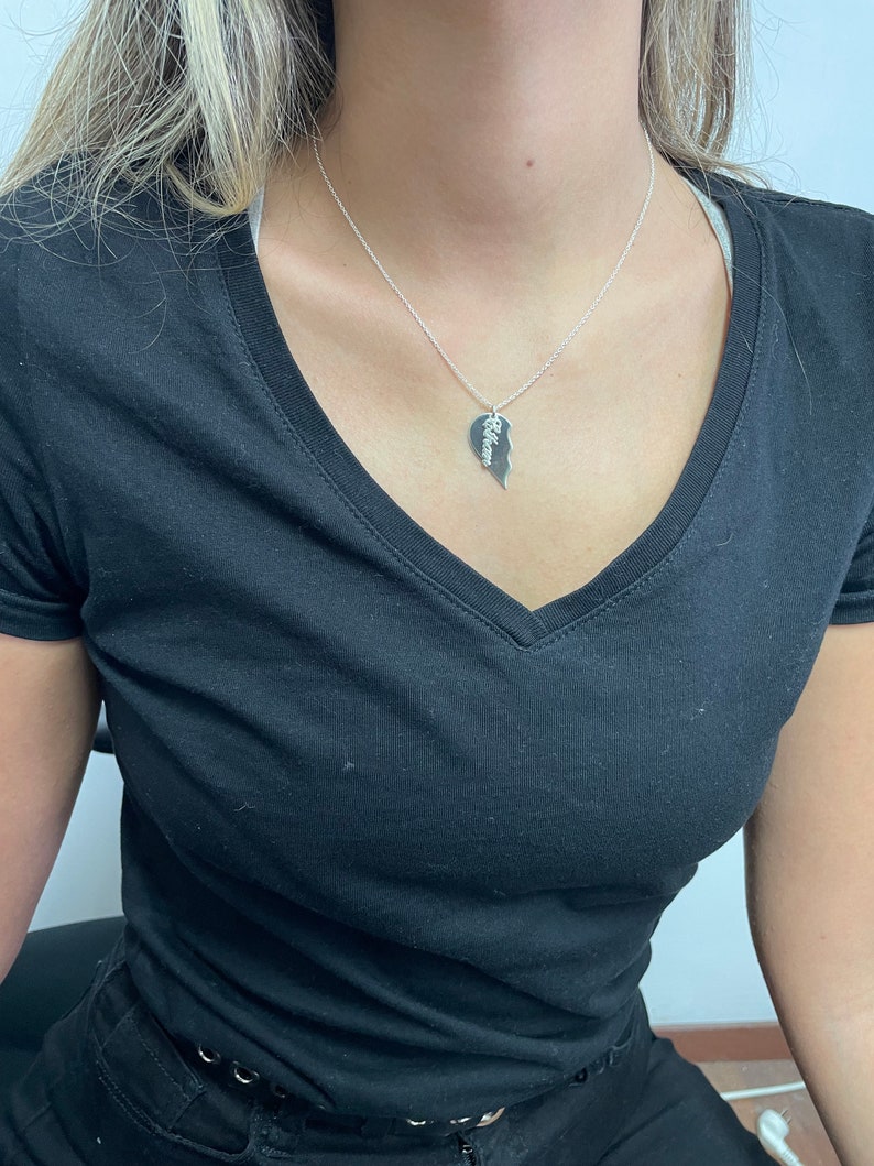May include: A silver necklace with a heart-shaped pendant that is split in half. The pendant has the word "Allison" engraved on it.