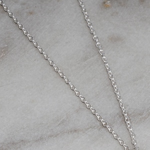 May include: A silver chain necklace with a delicate, cable chain design.