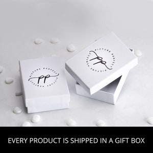 May include: White gift box with a black logo that says "Picture Perfect" in a circle. The box is open and the inside is white.