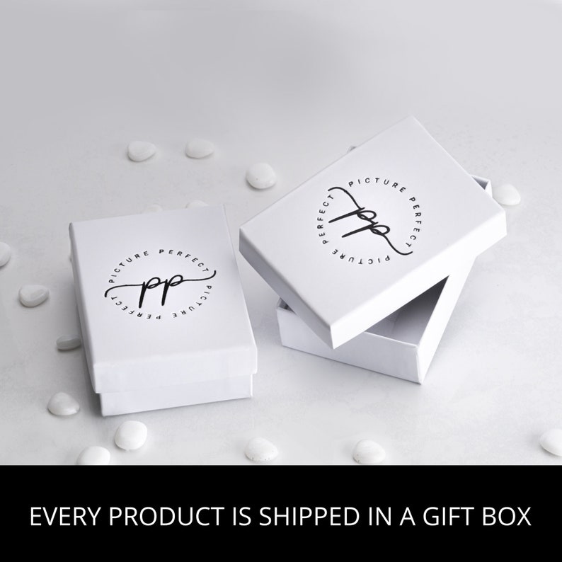 May include: White gift box with a black logo that says "Picture Perfect" in a circle. The box is open and the inside is white.