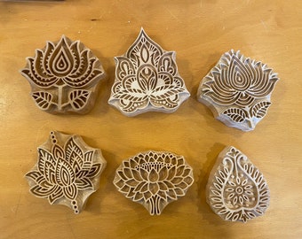 May include: Six wooden block printing stamps with intricate floral designs. The stamps are carved with detailed patterns of flowers, leaves, and paisley motifs. They are ideal for creating unique patterns on fabric, paper, or other surfaces.