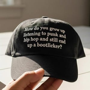 Gorra bordada con el texto "Cómo creces escuchando punk y hip hop y aun así terminas siendo un lamebotas", divertida gorra musical.