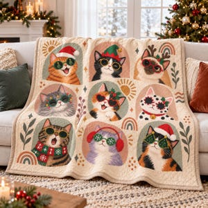 May include: A cream-colored quilted throw blanket featuring a grid of nine illustrated cats wearing festive holiday accessories like Santa hats, reindeer antlers, earmuffs, scarves, and Christmas-themed glasses, accented with small rainbows and leaves.