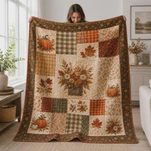 May include: A patchwork quilt featuring a seasonal autumn theme with blocks of orange pumpkins, brown maple leaves, floral patterns, and plaid textures. The quilt has a dark green border with a repeating leaf print and a central floral arrangement.