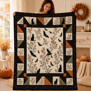 May include: A rectangular quilt featuring a cream-colored center panel with black cat silhouettes, flying bats, and orange berry branches. The border consists of alternating black floral fabric, solid orange triangles, and green patterned squares.