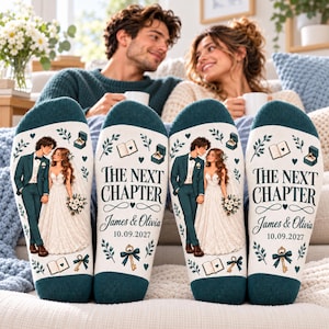 May include: A pair of dark teal and white socks featuring a printed illustration of a bride and groom, the text "THE NEXT CHAPTER", the names "James & Olivia", the date "10.09.2027", and small icons of an open book, a ring box, and a key.