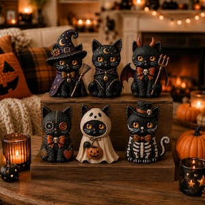 May include: A set of six black cat figurines arranged on a wooden stand. The cats are dressed in various costumes including a witch with a broom, a moon-adorned cat, a devil with wings and a trident, a stitched cat, a ghost, and a skeleton cat.