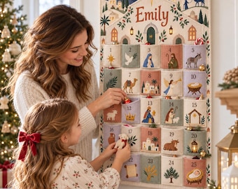 Könnte beinhalten: Ein hängender Adventskalender aus Stoff mit dem Namen Emily an der Oberseite, der fünfundzwanzig nummerierte Taschen mit weihnachtlichen Motiven wie Figuren, Tieren und Gebäuden in sanften Blau-, Grün- und Rottönen aufweist.