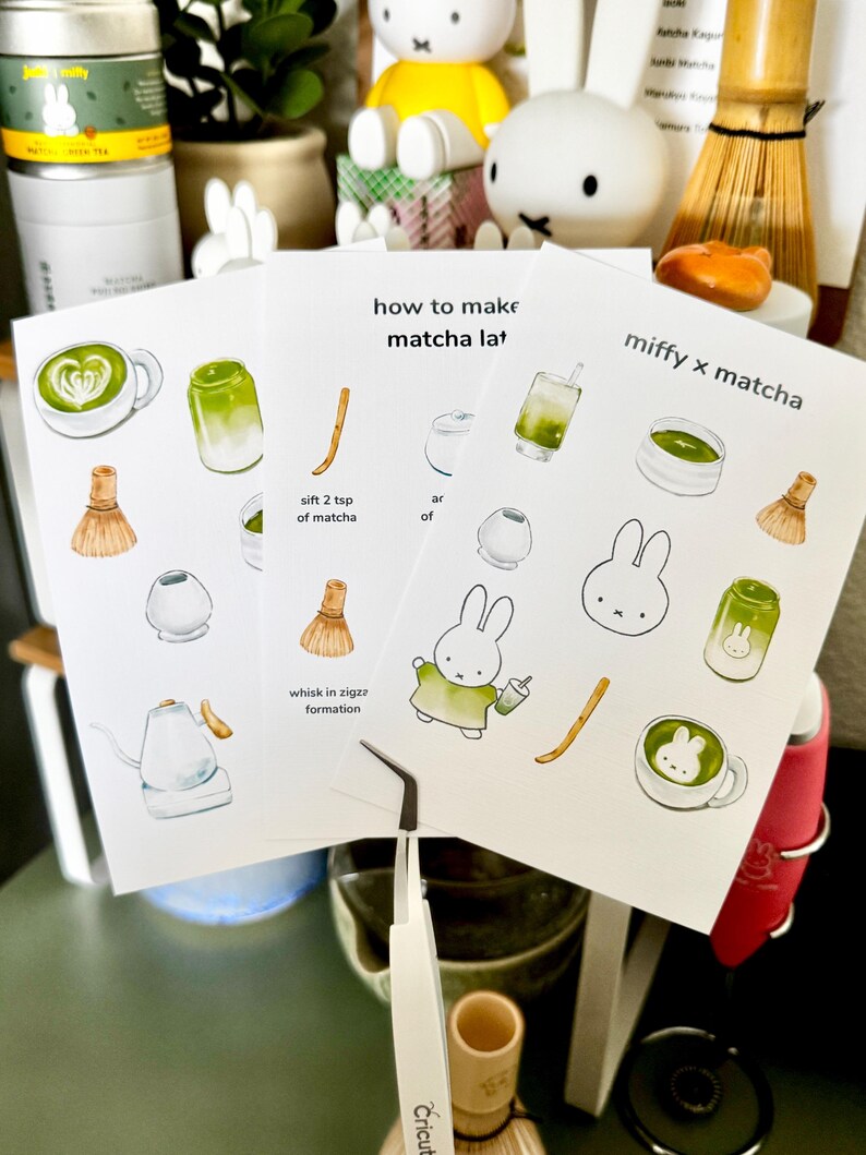 Op de afbeelding: Drie witte kaarten met matcha latte illustraties en tekst. E&eacute;n kaart leest "how to make matcha lat" en een andere "miffy x matcha". De kaarten tonen een garde, een konijn en een kopje matcha. Een pincet staat op de voorgrond.