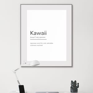May include: A black and white printable wall art print with the word "Kawaii" in bold, black text. The word is defined as a Japanese word for cute, adorable, and cuteness overload. The print is framed in a black frame and is sitting on a white desk with a lamp and a black cat figurine.