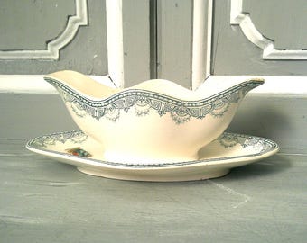 May include: A white porcelain gravy boat with a blue and white floral design. The boat is sitting on a matching saucer.
