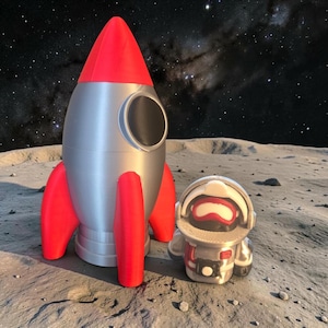 Puede incluir: Un cohete plateado con aletas rojas y un cono de nariz rojo está junto a una pequeña figura de astronauta. El astronauta lleva un traje espacial plateado con una visera roja y blanca. El fondo muestra un cielo estrellado y una superficie lunar.