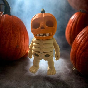 May include: A skeletal figure wearing a carved pumpkin head stands in front of a group of pumpkins. The figure is made of a light beige material and has a white skeleton design. The pumpkins are orange and have a smooth surface.