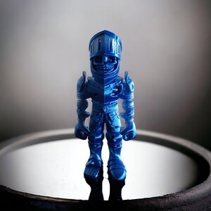 May include: A blue plastic toy knight figurine with a helmet and armor. The knight is standing on a reflective surface.