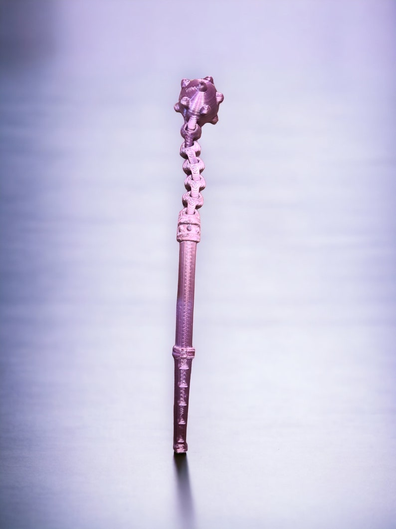 May include: A pink metal spiked ball on a chain attached to a long, thin, pink metal rod.