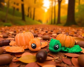 May include: Orange and green pumpkin-shaped figurines with large black eyes rest on a bed of fallen autumn leaves. The background features a blurred forest scene with a path leading into the distance, bathed in warm sunlight.