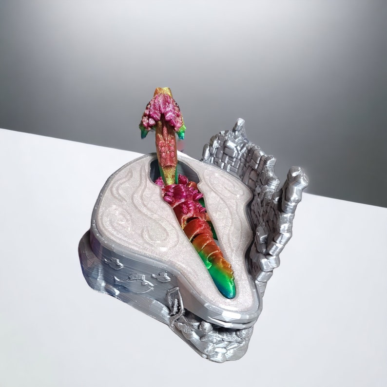 K&ouml;nnte beinhalten: Eine silberne 3D-gedruckte Drachenfigur mit schillernden Schuppen, die auf einem silbernen Sockel mit strukturierter Oberfl&auml;che sitzt. Der Kopf des Drachen ist erhoben und seine Fl&uuml;gel sind ausgebreitet.