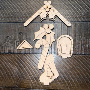 May include: Wooden Christmas-themed cutouts, including a holly sprig, candy cane, bell with a tree, stocking, and a triangle with the word "back". These unfinished wood pieces are perfect for holiday crafts.
