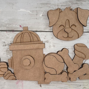 May include: Wooden craft cutouts of a dog, fire hydrant, bone, and ball. The dog has a happy expression and closed eyes. The fire hydrant has a detailed design. The bone and ball are simple shapes.