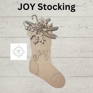 May include: A wooden Christmas stocking with the word "JOY" cut out. The stocking is decorated with a snowflake, pine needles, and a candy cane. The text "JOY Stocking" is at the top.