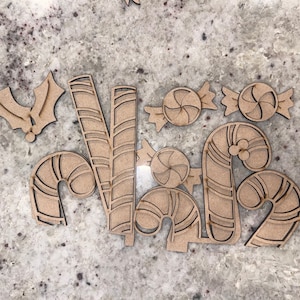 May include: A set of wooden Christmas ornaments featuring candy canes, candy, and holly. The ornaments are cut out and ready to be painted or decorated.