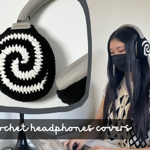 Puede incluir: Un par de fundas para auriculares de ganchillo en blanco y negro con un patrón de espiral. Las fundas se muestran en un par de auriculares con la palabra "SONY" en el lateral.