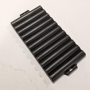 May include: Black cast iron bread baking pan with a ridged design. The pan has the text "L. Bread Baker", "Wagner Ware", "Sidney, Ohio", and "1236" embossed on the surface. The pan has two handles on the sides.