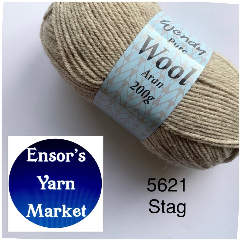 May include: A ball of Wendy Pure Wool Aran yarn in the colour Stag, a light beige. The yarn is labelled with the brand name, weight, and colour number. The ball is sitting on a white surface.