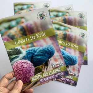 May include: A stack of colourful brochures with the text "Learn to Knit" and "Enjoy! Mindful and Relaxing. Try our basic patterns." The brochures feature a close-up of yarn balls in shades of blue, pink, and green.