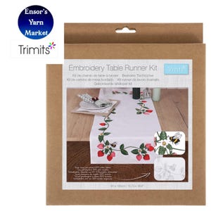 May include: A boxed embroidery table runner kit. The white runner has a strawberry and bee design. The kit includes the runner, measuring 40 x 100cm, and the Trimits logo. The box is brown.