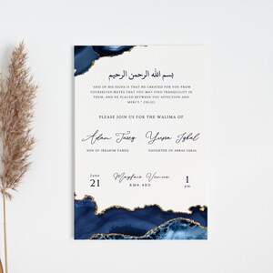 May include: A cream-coloured invitation card with navy blue and gold watercolour details. The card features elegant calligraphy and includes Arabic script, English text, and event details for a wedding.