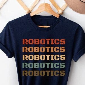 May include: A navy blue t-shirt with the word "Robotics" repeated five times in a retro rainbow colour scheme.