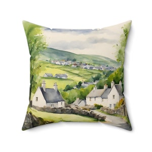 Peut inclure: Coussin carré avec une peinture à l'aquarelle d'un village dans une vallée. L'œuvre représente des maisons blanches aux toits gris, des collines verdoyantes et une route sinueuse. Le coussin a un aspect doux, sur le thème rural.