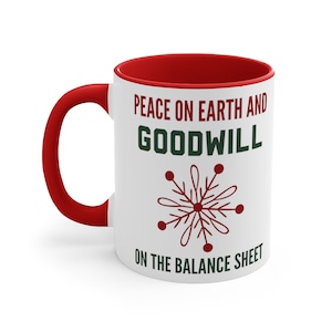 May include: White ceramic mug with a red interior and handle. The mug features the text "PEACE ON EARTH AND GOODWILL ON THE BALANCE SHEET" in red and green, along with a snowflake design. A festive holiday-themed mug.