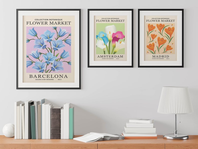 Puede incluir: Tres impresiones enmarcadas con un tema bot&aacute;nico. Cada impresi&oacute;n presenta una flor diferente y el nombre de una ciudad. La primera impresi&oacute;n muestra flores de campanilla azul y el texto "COLLECTION BOTANIQUE FLOWER MARKET BARCELONA". La segunda impresi&oacute;n muestra lirios calla blancos, rosas y azules y el texto "COLLECTION BOTANIQUE FLOWER MARKET AMSTERDAM". La tercera impresi&oacute;n muestra flores de azafr&aacute;n naranja y el texto "COLLECTION BOTANIQUE FLOWER MARKET MADRID".