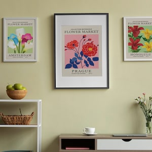 Puede incluir: Tres impresiones bot&aacute;nicas enmarcadas con el t&iacute;tulo "Flower Market" y los nombres de las ciudades "Amsterdam", "Praga" y "Honolulu". Cada impresi&oacute;n presenta un tipo de flor diferente en un dise&ntilde;o colorido y estilizado.
