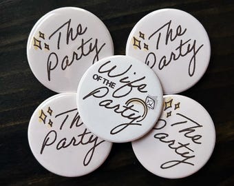 May include: Five pink round buttons with the text "The Party" in black script. One button has the text "Wife of the Party" with a gold ring and diamond graphic.