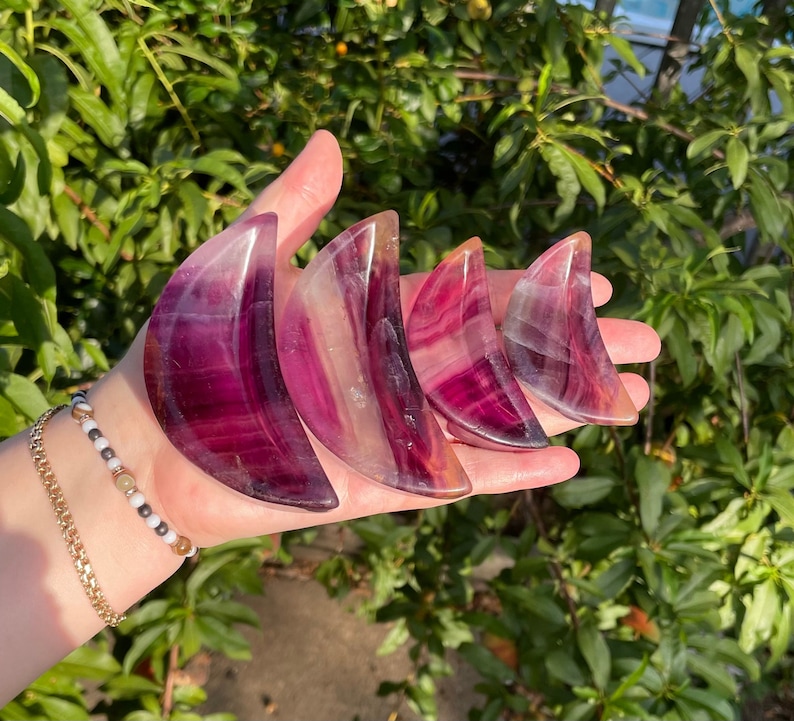 Peut inclure: Quatre cristaux de fluorine en forme de croissant de lune dans des tons de rose, violet et blanc. Les cristaux sont dispos&eacute;s en rang&eacute;e, le plus grand &agrave; gauche et le plus petit &agrave; droite.