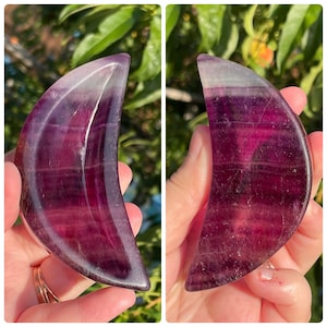 Peut inclure: Un cristal de fluorite violet et blanc sculpt&eacute; en forme de croissant de lune. Le cristal est translucide et pr&eacute;sente un motif stri&eacute;.