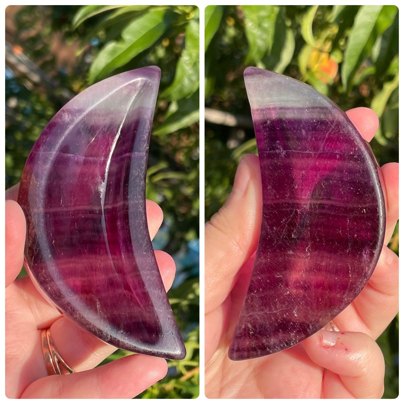 Peut inclure: Un cristal de fluorite violet et blanc sculpt&eacute; en forme de croissant de lune. Le cristal est translucide et pr&eacute;sente un motif stri&eacute;.