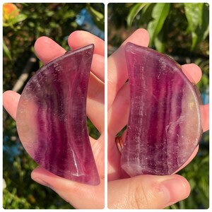 Peut inclure: Une pi&egrave;ce de cristal de fluorine en forme de croissant de lune, de couleur violette et verte. Le cristal est poli et a une surface lisse et brillante.