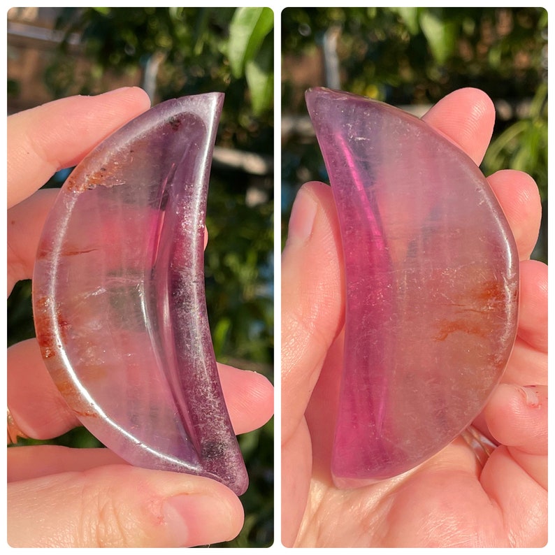 Peut inclure: Un cristal en forme de croissant de lune avec une teinte rose et violette. Le cristal est translucide et a une surface lisse et polie.