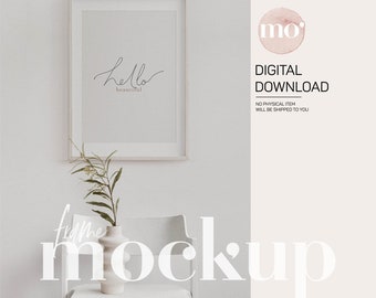 May include: A white frame mockup with a simple black and white print that says "hello beautiful" inside the frame. The frame is sitting on a white chair with a white vase and green plant.