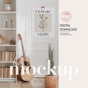 Może przedstawiać: Mockup cyfrowego pobrania przedstawiający wydruk do druku na ścianę z minimalistycznym rysunkiem kwiatu i tekstem "Un beau matin" po francusku. Wydruk jest oprawiony i wyświetlany na białej ścianie z regałem na książki, gitarą i kaktusową rośliną w doniczce z terakoty.