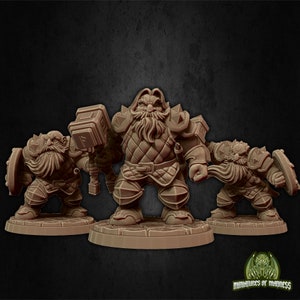May include: Three miniature figurines of dwarves, each with a beard and wearing armour. The dwarf in the centre is holding a hammer, while the other two are holding shields. The figurines are painted in shades of brown and grey.