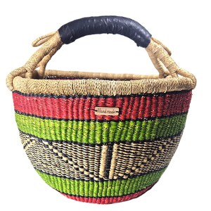 Op de afbeelding: Een ronde gevlochten mand met horizontale strepen in rood, limoengroen en zwart. De mand heeft een natuurlijke beige rand en een enkel handvat omwikkeld met zwart materiaal. Een klein houten label met "Hand made" is bevestigd.