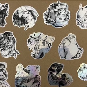 Könnte beinhalten: Ein Set mit 12 schwarz-weißen Aufklebern mit skurrilen, cartoonartigen Kreaturen. Die Aufkleber sind auf einem silbernen holografischen Hintergrund gedruckt.