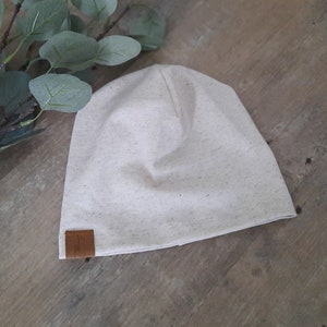 Könnte beinhalten: Eine beige Mütze mit einem braunen Lederflicken an der Seite.